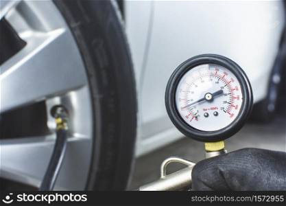 Mechanic testing the tire pressure with tire pressure gauge
