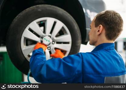 Mechanic unscrews car wheel, tire service. Automobile repair, vehicle maintenance. Mechanic unscrews the wheel, tire service