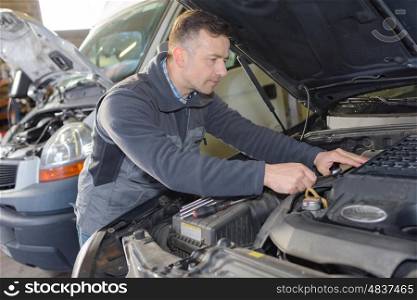 mechanic using laptop while repairing car in garage
