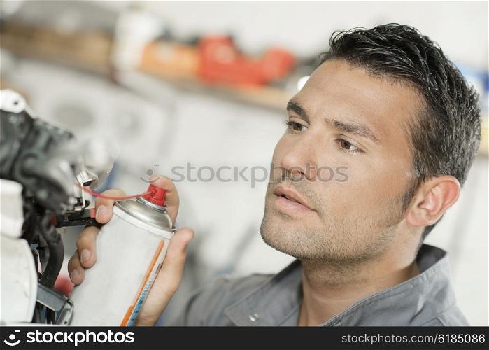 Mechanic using lubrication spray