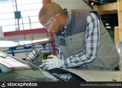 mechanic using repairing equipment to fix damaged windshield