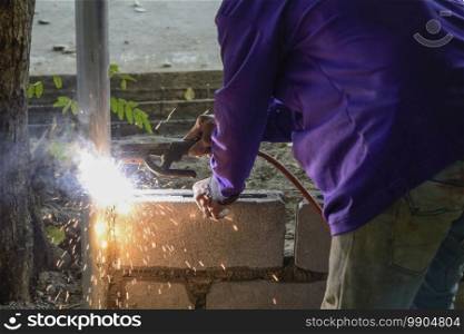 Mechanic workers are welding iron without protective gloves.
