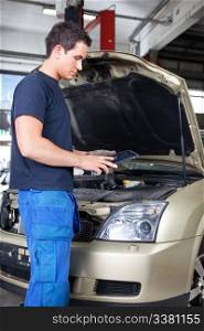 Mechanic working on a digital tablet while standing besides car