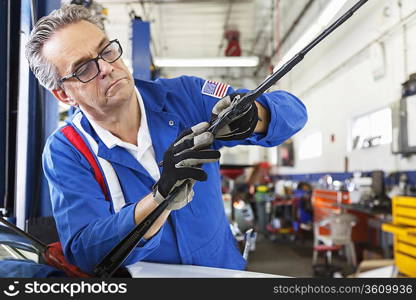 Mechanic working on windshield wipers of car