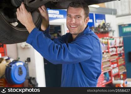 Mechanic working under car smiling