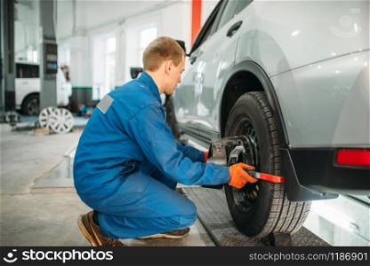 Mechanic works on collapse of convergence stand in auto-service. Computer diagnostic of car suspension. Mechanic works on collapse of convergence stand