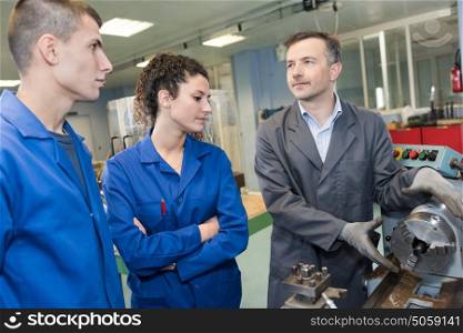 mechanical engineer showing apprentice a machine