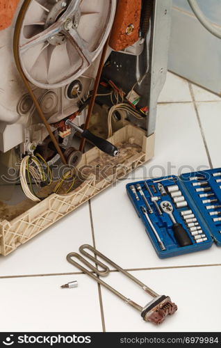 Mechanical industrial domestic electrical engineering concept. Washing machine during repair. Broken laundromat with heater removed next to tool set.. Washing machine during repair.