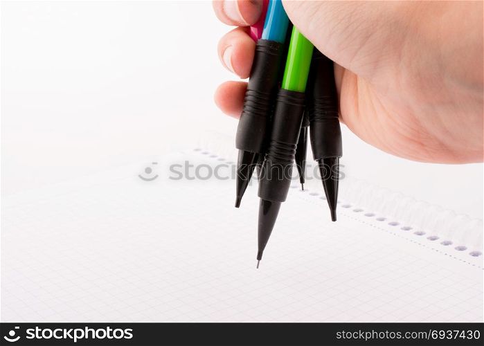 mechanical pencils of various color in hand on white background