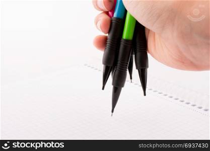 mechanical pencils of various color in hand on white background