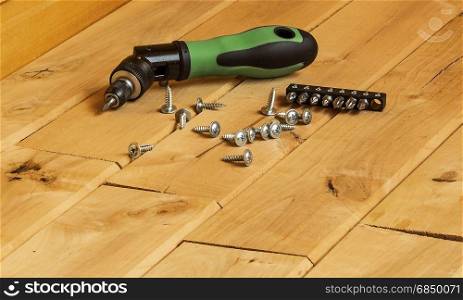 Mechanical screwdriver to tighten the screws on a wooden surface