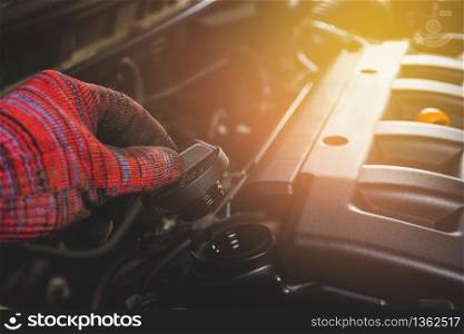 Mechanics hand open oil cap of car engine for maintenance service in vehicle repair garage.