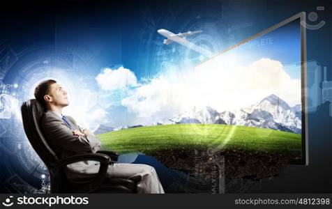 Media technologies. Young businessman sitting in chair behind tv