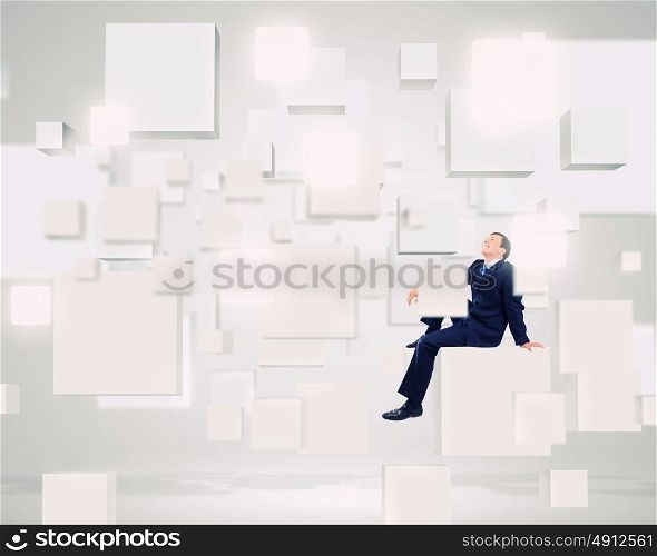 Media technologies. Young smiling businessman sitting on white cube