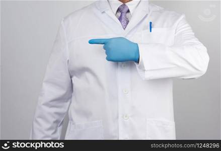 medic man in white coat with buttons, on hands wearing blue sterile gloves, showing hand gesture indicating the subject, white background