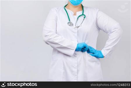 medic woman in white coat and mask, wearing blue medical latex gloves on her hands, copy space