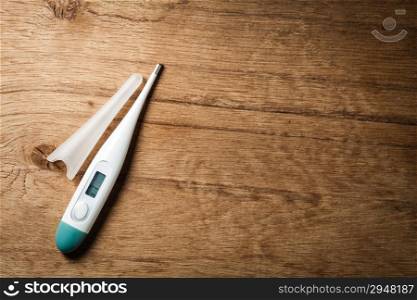 Medical background. Closeup of electronic thermometer on wooden background. Fever.