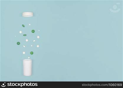 Medical background with pills. White and green pills pour out of a bottle on a blue background. Flat lay concept. Copy space.. Medical background with pills and bottle.