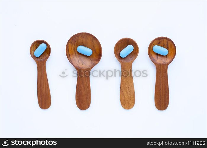 Medical blue pills with he wooden spoon on white background. Copy space