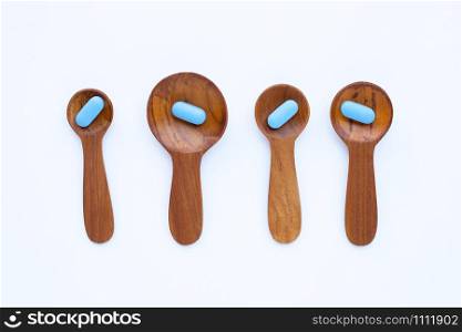 Medical blue pills with he wooden spoon on white background. Copy space