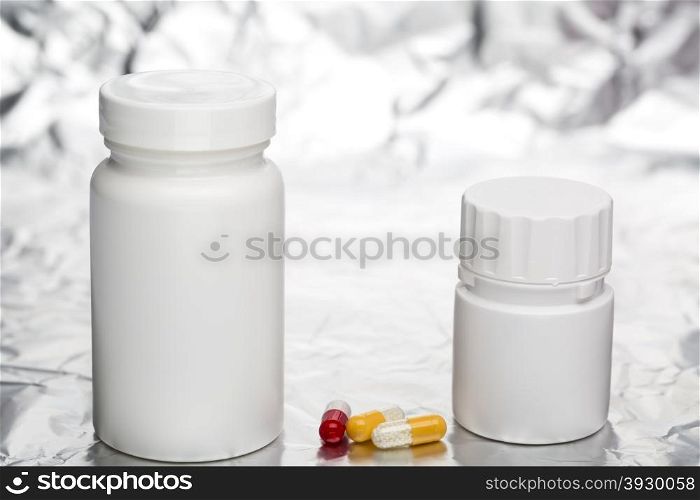 Medical capsules with white plastic bottle. Capsules with medical bottle on foil background