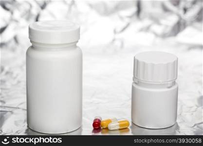 Medical capsules with white plastic bottle. Capsules with medical bottle on foil background