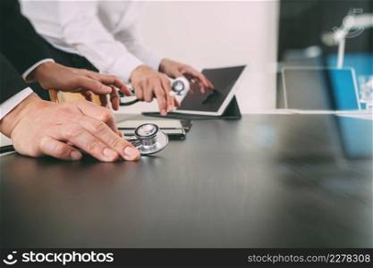 Medical co working concept,Doctor working with smart phone and digital tablet and laptop computer to meeting his team in modern office at hospital with glass reflected view