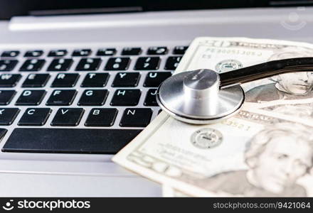 Medical cost concept. Stethoscope on top of money on laptop keyboard. Stethoscope on dollar bills on top of laptop keyboard