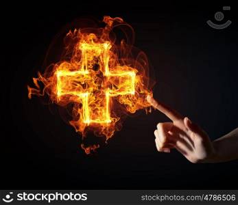 Medical cross icon. Finger touch glowing light cross sign on dark background