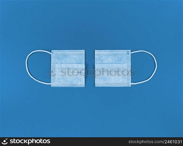 Medical disposable face mask cut in half on blue background.. Medical disposable face mask cut in half on a blue background.