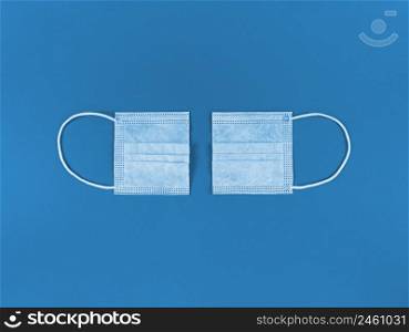 Medical disposable face mask cut in half on blue background.. Medical disposable face mask cut in half on a blue background.