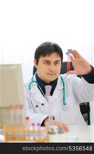 Medical doctor checking tube with blood sample