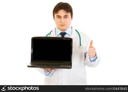 Medical doctor holding laptops with blank screen and showing thumbs up gesture isolated on white&#xA;
