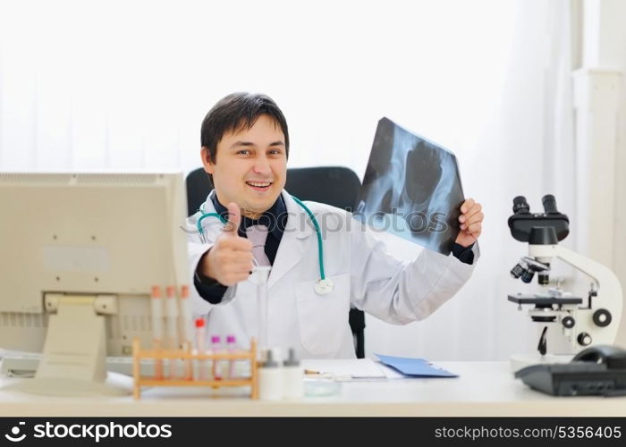 Medical doctor holding patients roentgen and showing thumbs up