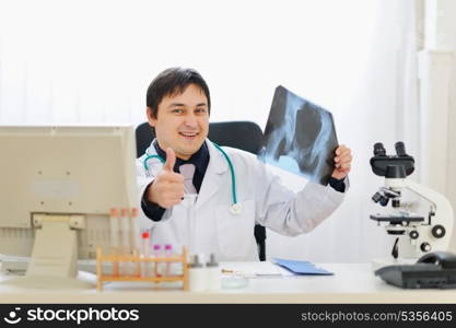 Medical doctor holding patients roentgen and showing thumbs up