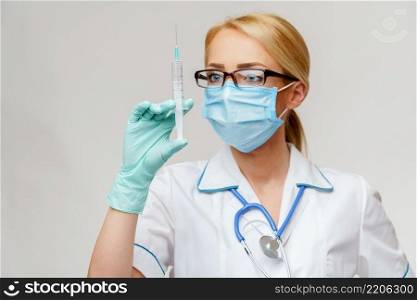 medical doctor nurse woman wearing protective mask and gloves - holding syringe.. medical doctor nurse woman wearing protective mask and gloves - holding syringe