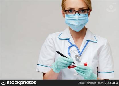 medical doctor nurse woman wearing protective mask and gloves - making mark by pen on virus blood test tube.. medical doctor nurse woman wearing protective mask and gloves - making mark by pen on virus blood test tube