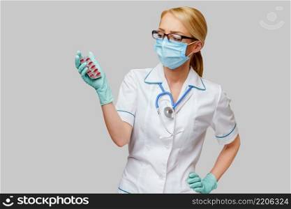 medical doctor nurse woman wearing protective mask and rubber or latex gloves - holding blisters of pills.. medical doctor nurse woman wearing protective mask and rubber or latex gloves - holding blisters of pills
