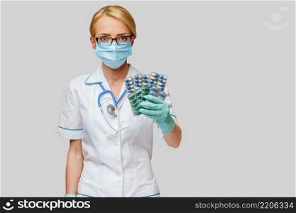 medical doctor nurse woman wearing protective mask and rubber or latex gloves - holding blisters of pills.. medical doctor nurse woman wearing protective mask and rubber or latex gloves - holding blisters of pills