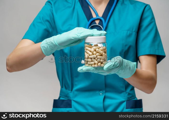 medical doctor nurse woman wearing protective mask and rubber or latex gloves - holding pills.. medical doctor nurse woman wearing protective mask and rubber or latex gloves - holding pills