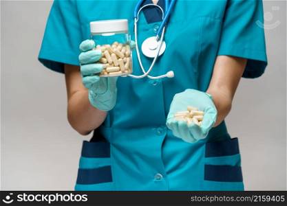 medical doctor nurse woman wearing protective mask and rubber or latex gloves - holding pills.. medical doctor nurse woman wearing protective mask and rubber or latex gloves - holding pills