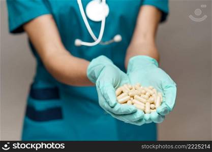 medical doctor nurse woman wearing protective mask and rubber or latex gloves - holding pills.. medical doctor nurse woman wearing protective mask and rubber or latex gloves - holding pills