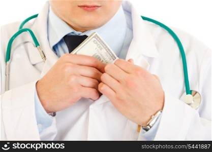 Medical doctor putting money in pocket isolated on white. Close-up.&#xA;