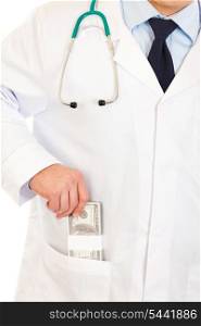Medical doctor putting money in pocket robe isolated on white. Close-up.&#xA;
