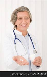 Medical doctor senior female holding pills smiling professional portrait