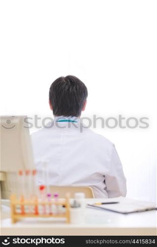 Medical doctor siting with his back to table at cabinet