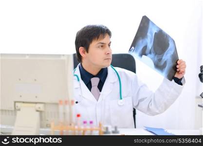 Medical doctor sitting at office table and analyzing patients roentgen&#xA;