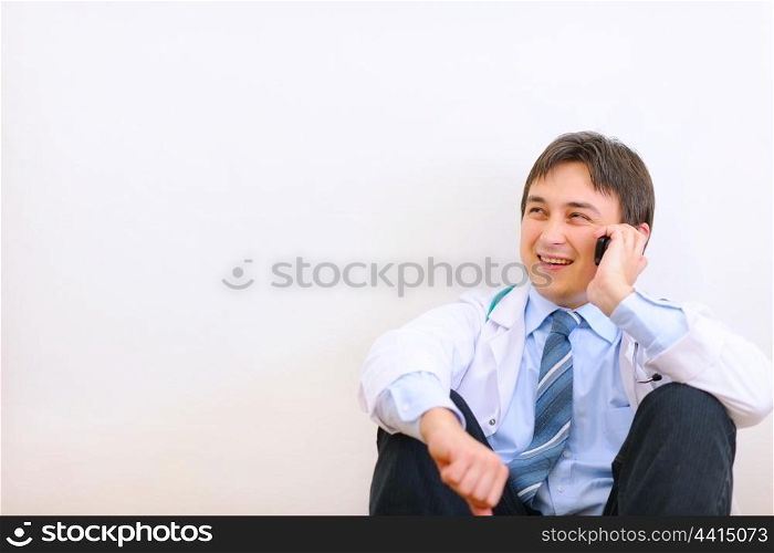 Medical doctor sitting on floor and talking mobile