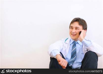 Medical doctor sitting on floor and talking mobile