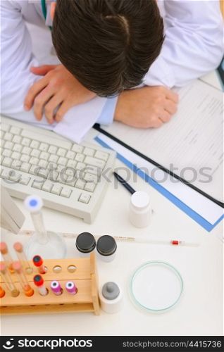 Medical doctor sleeping on desk with medical stuff. Top view